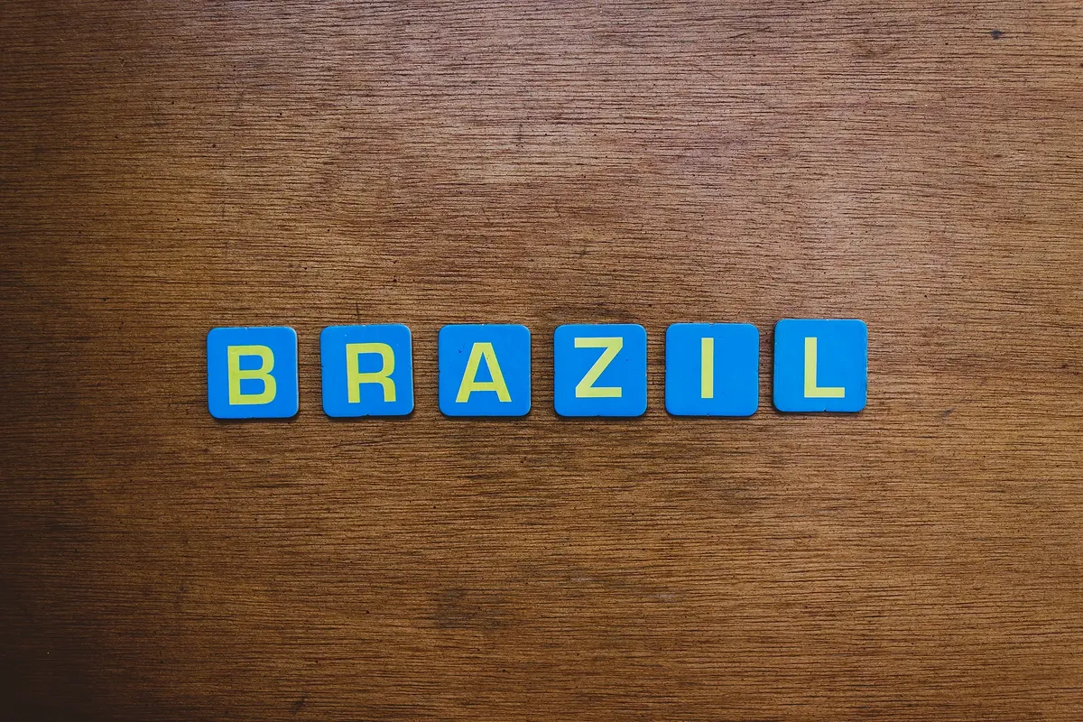 Close-up image of the word 'Brazil' spelled with blue tiles on a wooden surface, flat lay style.