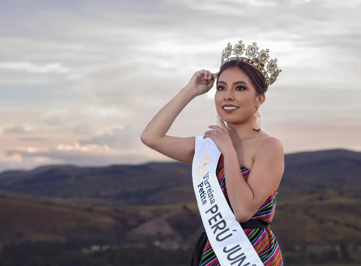A stunning Peruvian beauty queen poses with her crown against a scenic sunset in Junín.