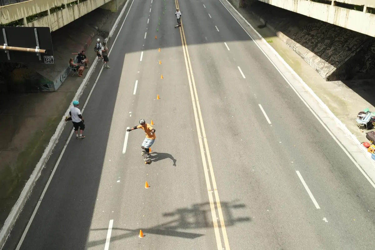 A skateboarder maneuvers through cones on an open street in São Paulo, Brazil.
